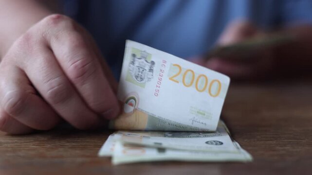 Defocused 4K video close up. 60 fps. Male hand counts Serbian paper banknote 2000 dinar bill. Two thousand dinar bill. Concept of cash money, salary, budget, wages, bank note, pay tax, loan, debt, buy