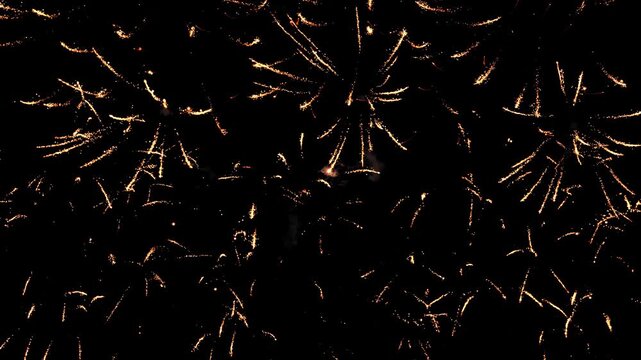 Bright sparks of fireworks in the dark night sky are multicolored