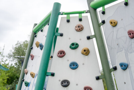 Children climb a colorful rock wall at an outdoor playground. Outdoor play and fitness themes: childhood activity, teamwork, recreation, summer fun.
