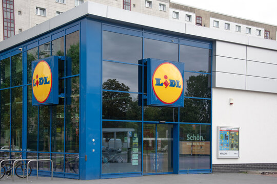 Berlin, Germany - 16 August 2026. A Lidl supermarket sign mounted on a glass storefront outside a retail grocery store. Retail, grocery, discount, brand, shopping, storefront, signage, economy.
