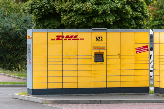 Berlin, Germany - 16 August 2026. Yellow DHL parcel locker stands at an outdoor pickup station by a street. Self-service shipping hub for delivery, logistics, e-commerce, urban infrastructure.