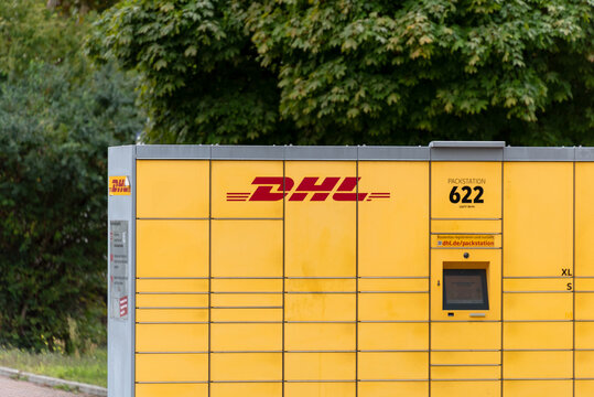Berlin, Germany - 16 August 2026. Yellow DHL parcel locker stands at an outdoor pickup station by a street. Self-service shipping hub for delivery, logistics, e-commerce, urban infrastructure.