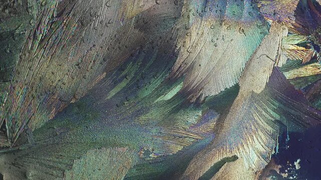 Urea polycrystalline texture observed under polarized light microscope while rotating polarization filter to showcase intense organic mineral color shift and crystal lattice birefringence dynamics