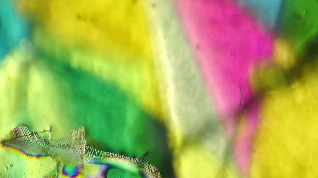 Real time urea crystallization dynamic process observed under polarized light microscope showing carbamide chemical crystal formation and intense organic interference colors for study archive