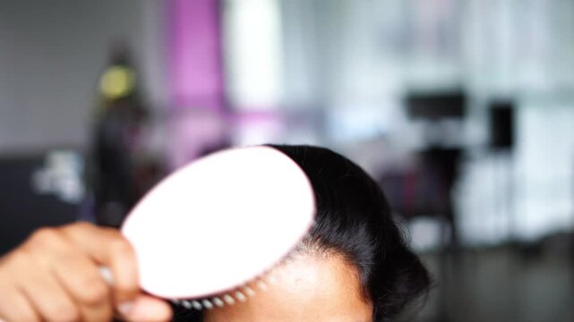 Front View of Woman Gently Combing Her Hair with White Comb in Personal Grooming Routine.