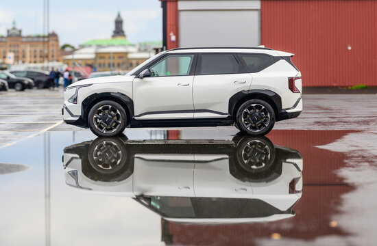 Gothenburg, Sweden - August 23 2026: White Kia EV9 electric SUV reflected in rainy pavement.