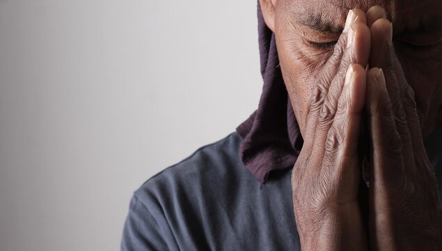 praying to god with hands showing his religious faith with God Caribbean man praying with background with people stock photo stock image