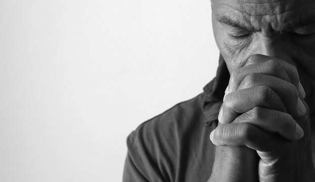 praying to god with hands showing his religious faith with God Caribbean man praying with background with people stock photo stock image