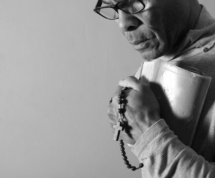 praying to god with hands showing his religious faith with God Caribbean man praying with background with people stock photo stock image