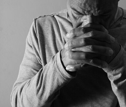 praying to god with hands showing his religious faith with God Caribbean man praying with background with people stock photo stock image