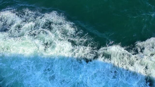 Powerful ship wake creating white foam on dark blue ocean water