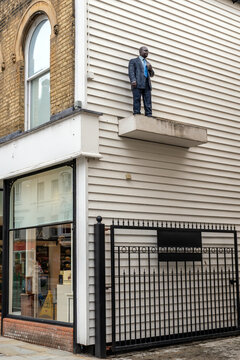 Sculpture titled Man with Cup by British artist Sean Henry, located on an upper ledge outside the Fenwick department store in Colchester, Essex