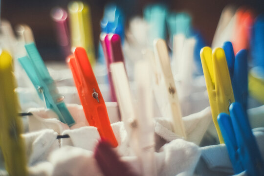 Close-up of colorful plastic clothespins on white fabric, with a soft blurred background. A vintage, everyday scene for laundry, home and lifestyle projects