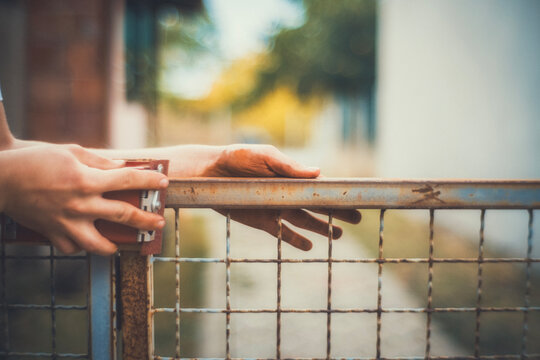 Close-up of hands using a sanding block to smooth a rusty metal fence before painting. Motion blur adds a raw, authentic feel. DIY restoration photo for craft and renovation projects