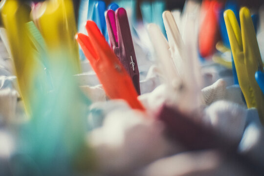 Close-up of colorful plastic clothespins on white fabric, with a soft blurred background. A vintage, everyday scene for laundry, home and lifestyle projects