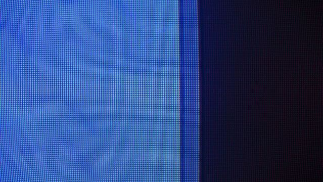 macro close-up of an LCD monitor showing a dense RGB subpixel grid with vibrant blue, cyan, and purple colors transitioning into a dark screen area.