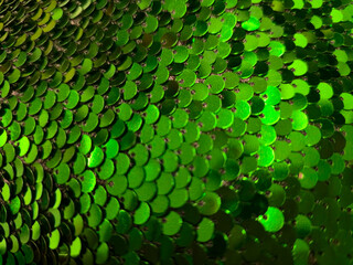 Green sequins close up, blurred Christmas and New Year festive background with soft bokeh, shimmering sequin surface with copy space. Holiday party concept, grainy film texture, high quality photo © Татьяна Швец