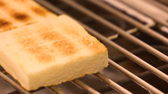 Golden toasted bread slice resting on a metal grill rack with char marks