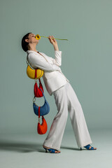 Naklejka premium Woman leaning back with gerbera and chained colorful moon bags