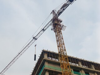 Heavy machinery yellow tower crane actively building a multi-story urban development project. © Salman