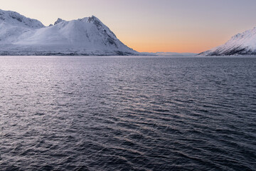 Entrance to a majestic fjord flanked by snow-covered mountains during polar twilight in Northern Norway © Alberto