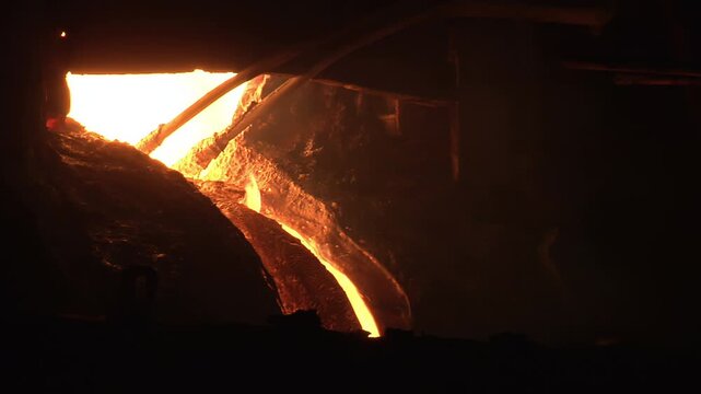 Blast furnace electrodes, hot liquid iron flowing trough. Glowing foundry heat.