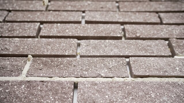 Brown speckled bricks with white aggregate laid in running bond pattern with fresh mortar, building material background