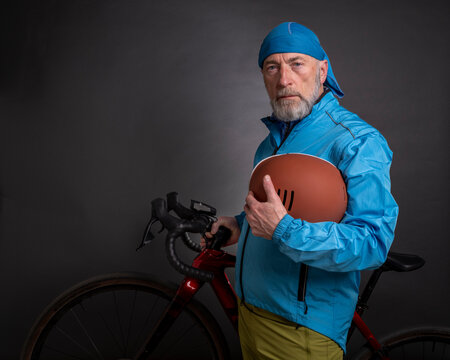 portrait of senior male cyclist wearing biking jacket and holding a helmet