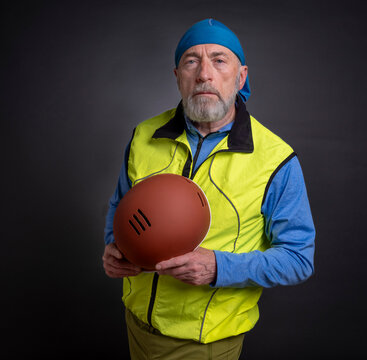portrait of senior male cyclist wearing biking vest and holding a helmet