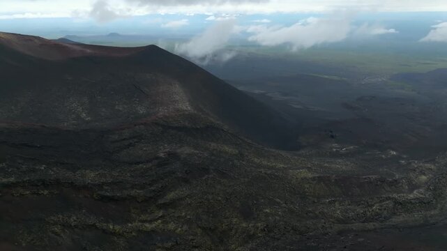 Cinematic aerial footage showcasing the cinder cone crater of the northern fissure eruption under a cloudy sky in Kamchatka Krai, Russia, revealing dramatic volcanic wilderness