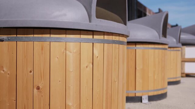 Close up of wooden outdoor trash bins with gray protective lids