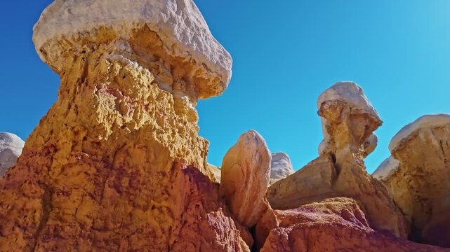 Towering white-capped hoodoo rock formations rise against a vibrant blue sky at Paint Mines Interpretive Park in Calhan, Colorado