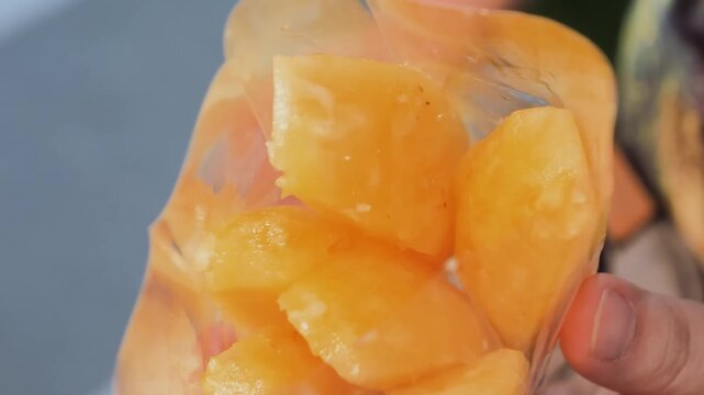 A detailed, close-up shot of bright yellow, freshly cut pineapple chunks sitting inside a transparent plastic bag.