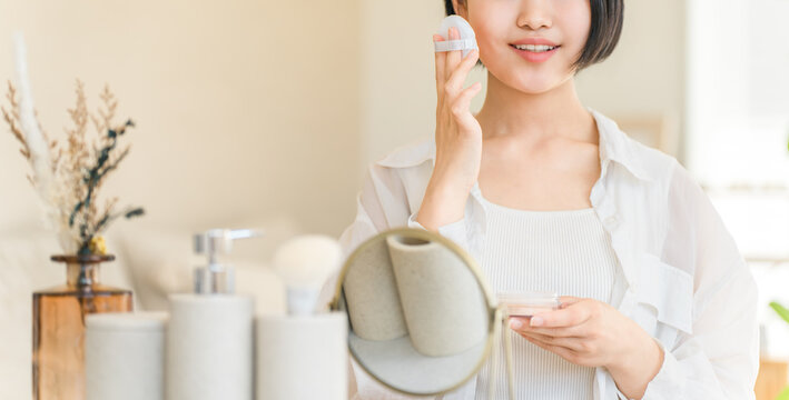 A teenage girl applying face powder while looking in a mirror
