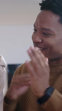 Vertical video: Laughing dad in sweater high-fiving in kitchen as child reaching for pumpkin, bowl