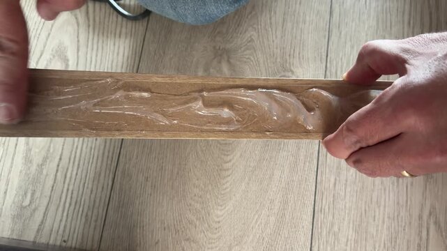 Handyman spreading wood glue on skirting board