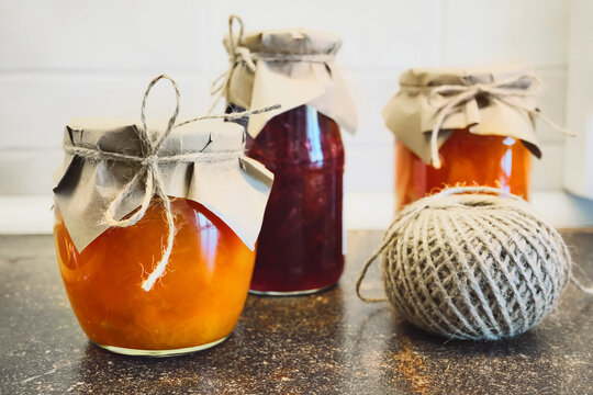 Glass jars filled with homemade fruit preserves and ball of twine ready for crafting