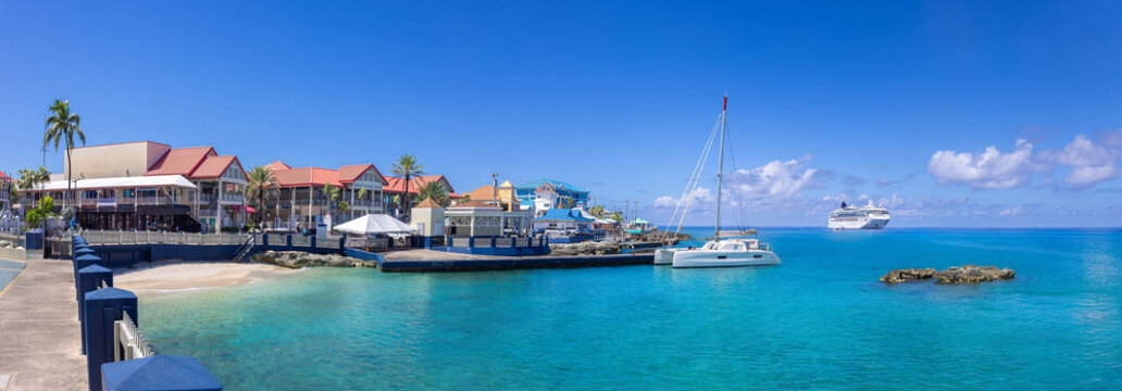 Sailing catamaran anchored in the turquoise water near the waterfront of George Town Grand Cayman. City panorama and skyline