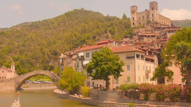 Static wide shot of Dolceacqua medieval hilltop village, Doria castle, Roman arch bridge over Nervia River.