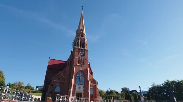 Wide exterior view of a historic church and tall bell tower under a clear blue sky in Cacica, Romania.