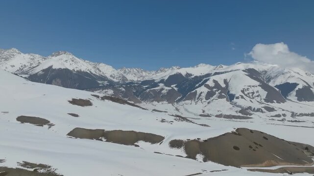 Scenic footage of snow covered peaks and ridges in Grigorievka Gorge within the Issyk-Kul Region of Kyrgyzstan showcasing pristine alpine wilderness under a clear blue sky