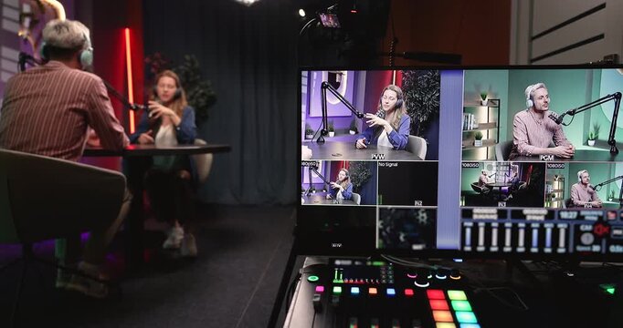 Media content creators duo in headphones talking into microphones at studio desk producing live podcast using portable digital workstation for high quality professional audio and video recording
