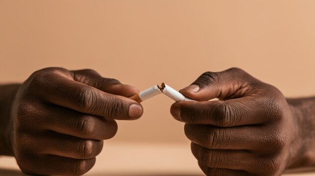 Close-up of dark-skinned hands breaking cigarette in half symbolizing smoking cessation and quitting unhealthy habit for better lifestyle