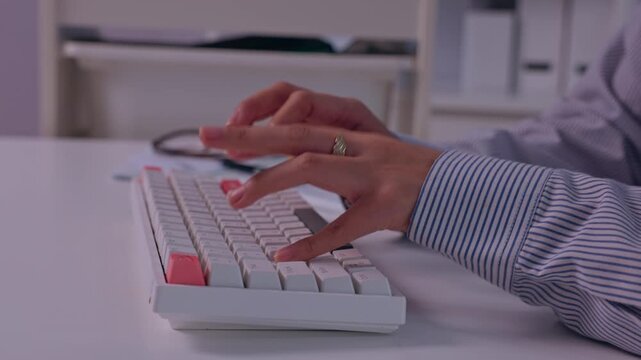 Hands Typing on White Computer Keyboard at Desk, Striped Shirt Sleeves Visible in Quiet Office Workspace, Capturing Focused Daily Work and Modern Technology
