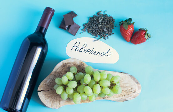 Foods containing a variety of beneficial polyphenols. Grapes, red wine, garlic, chocolate, green tea, nuts, and strawberries, shown in a close-up against a light background.