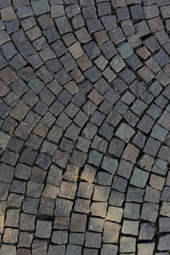Gray porphyry cobblestone pavement laid in a fan pattern, background texture