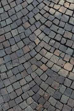 Gray porphyry cobblestone pavement laid in a fan pattern, background texture