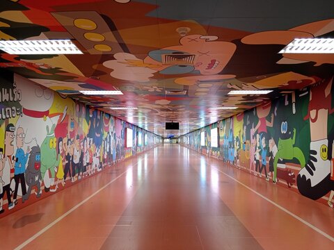 Bangkok, Thailand - January 18, 2026: A long tunnel at Bang Sue MRT station displays colorful art on the walls. People walk through the vibrant space in Bangkok during the day.