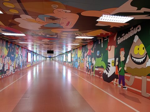 Bangkok, Thailand - January 18, 2026: A long tunnel at Bang Sue MRT station displays colorful art on the walls. People walk through the vibrant space in Bangkok during the day.