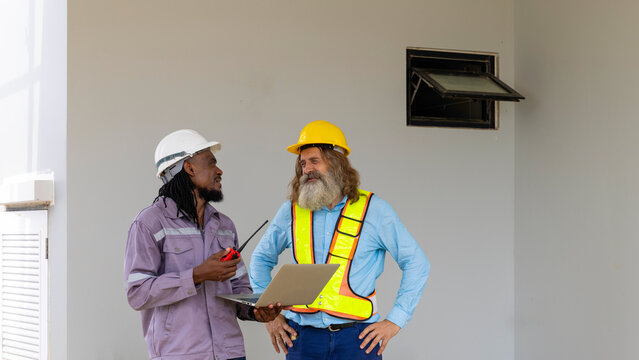Two construction workers from different generations using a laptop to review progress together, highlighting teamwork, shared experience, and learning in a contruction place